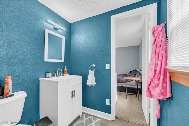 bathroom with vanity, toilet, and a textured ceiling