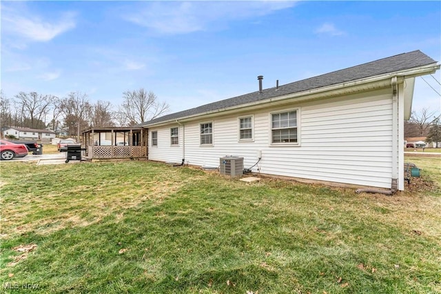 rear view of property featuring a yard and central AC unit