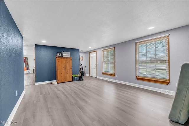 unfurnished living room featuring hardwood / wood-style floors and a textured ceiling