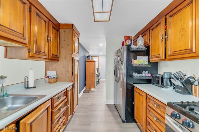 kitchen featuring stainless steel range with gas stovetop, sink, and light wood-type flooring