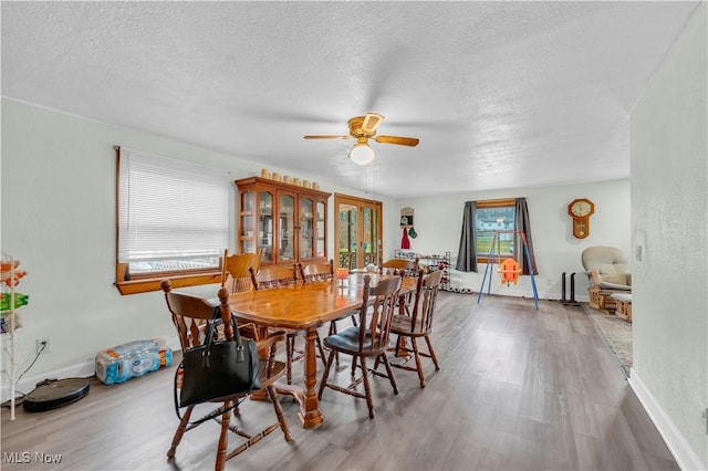 dining space with ceiling fan, wood-type flooring, and a textured ceiling