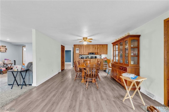 dining space with light hardwood / wood-style floors and ceiling fan