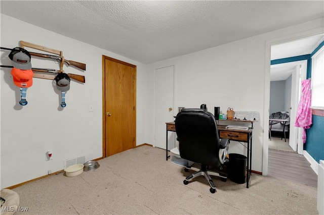 carpeted office with a textured ceiling