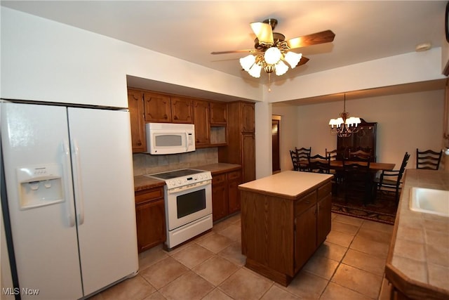 kitchen featuring light tile patterned floors, white appliances, decorative backsplash, a kitchen island, and decorative light fixtures