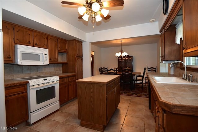 kitchen with sink, white appliances, backsplash, a kitchen island, and decorative light fixtures