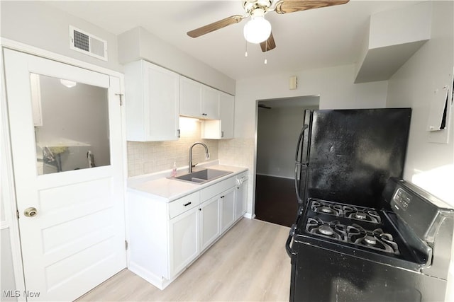 kitchen with white cabinetry, backsplash, sink, and black appliances