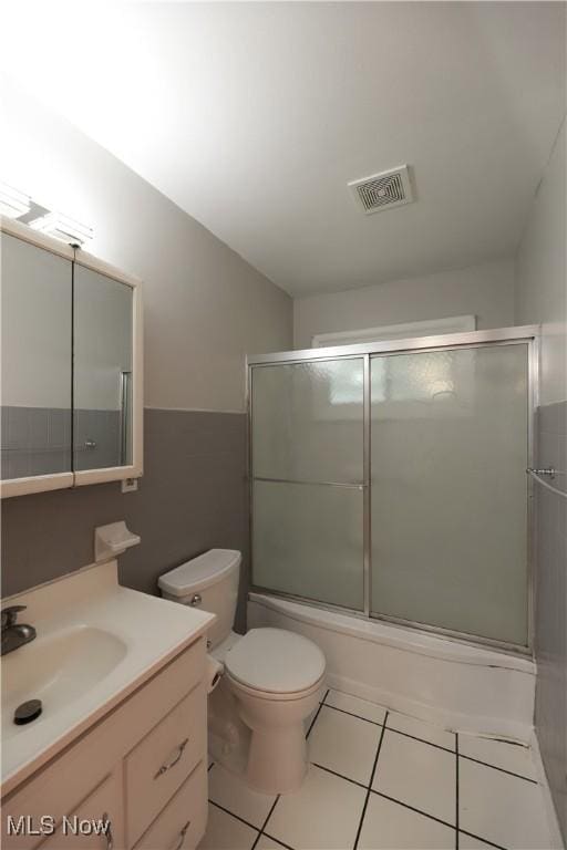 full bathroom with vanity, tile patterned floors, shower / bath combination with glass door, and toilet