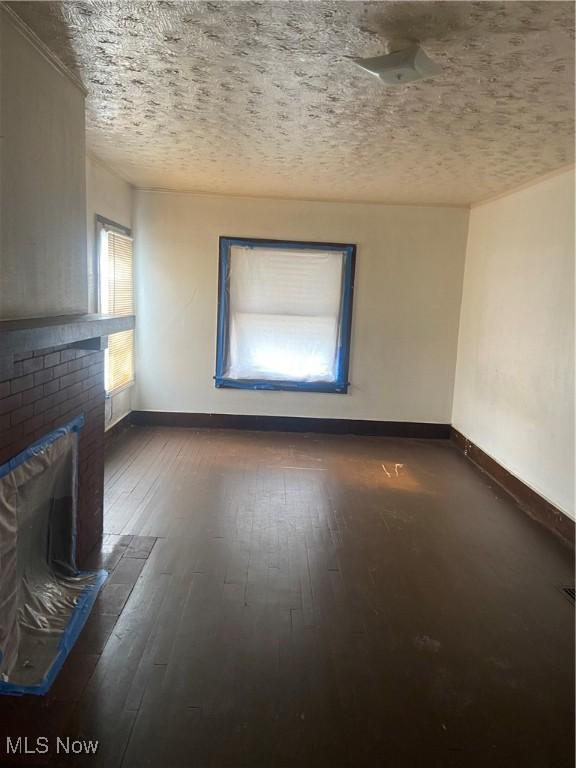 unfurnished living room with dark hardwood / wood-style flooring, a textured ceiling, and a fireplace