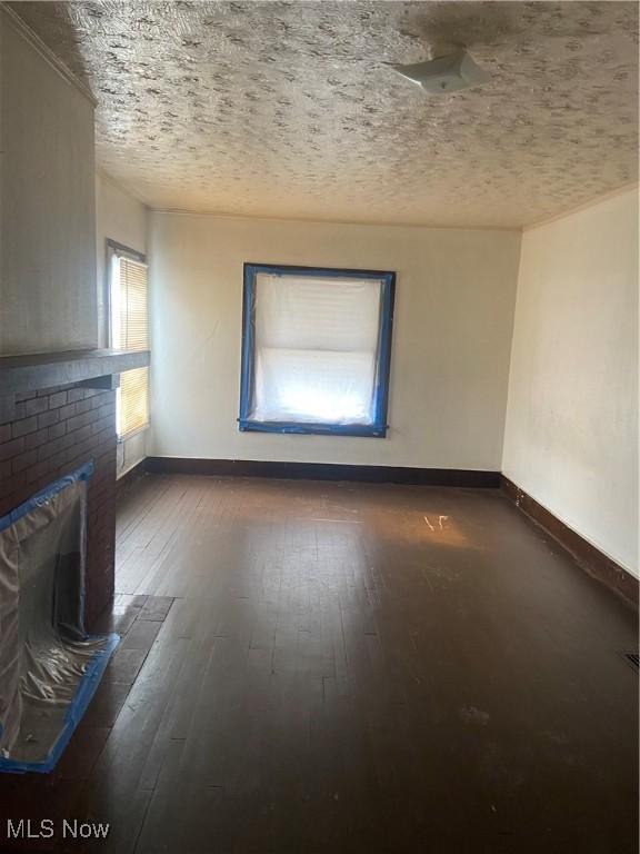 unfurnished living room featuring baseboards, hardwood / wood-style floors, and a brick fireplace