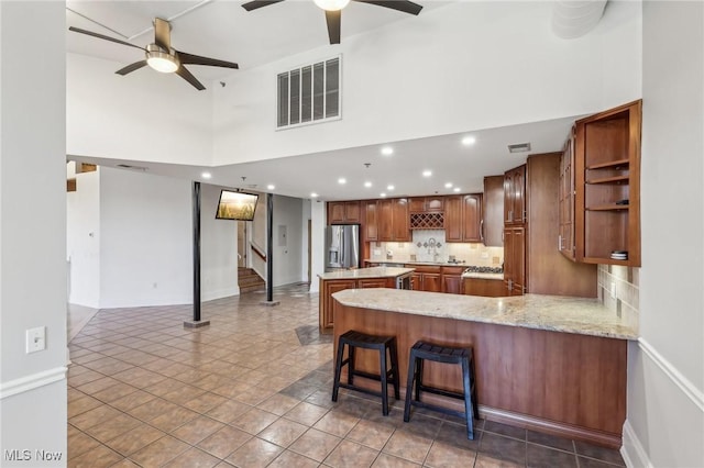 kitchen with a kitchen breakfast bar, a kitchen island, stainless steel fridge with ice dispenser, decorative backsplash, and kitchen peninsula