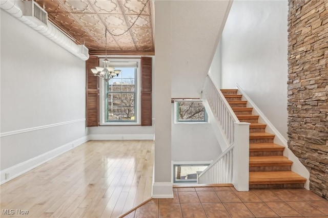 staircase featuring an inviting chandelier, hardwood / wood-style flooring, and a high ceiling