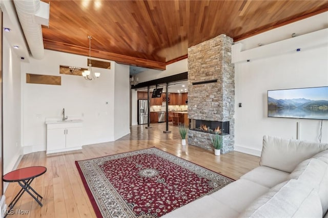 living room featuring sink, a fireplace, wooden ceiling, a chandelier, and light wood-type flooring