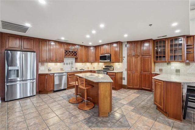 kitchen with stainless steel appliances, light stone countertops, a center island, and a breakfast bar