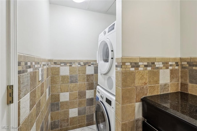 washroom featuring stacked washer / dryer and tile walls