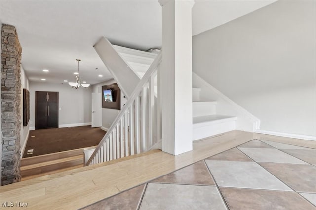 staircase featuring a chandelier, tile patterned flooring, and decorative columns