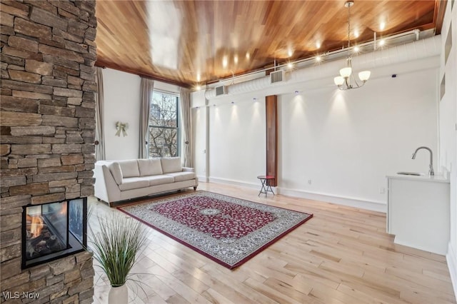 living room featuring sink, a fireplace, wooden ceiling, and light hardwood / wood-style floors