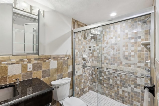 bathroom featuring tile walls, an enclosed shower, vanity, and toilet