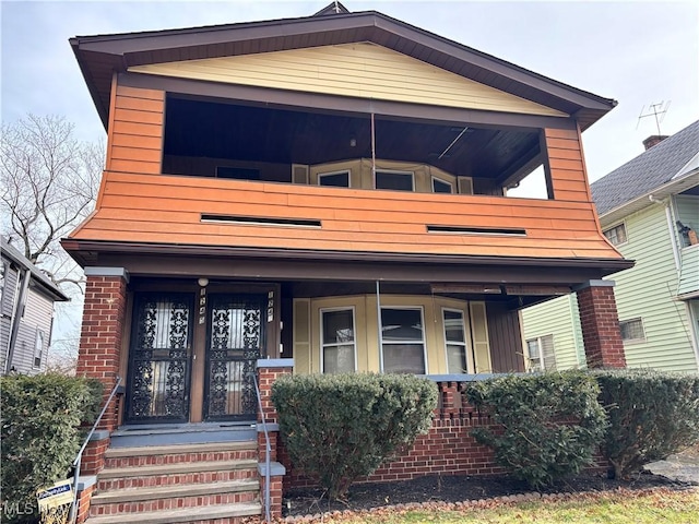 1245 E 137th St, East Cleveland, OH 44112 - view of front of property featuring covered porch, brick siding, and a balcony