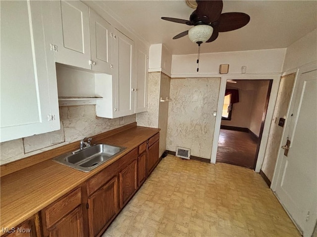 1245 E 137th St, East Cleveland, OH 44112 - kitchen with visible vents, decorative backsplash, baseboards, ceiling fan, and a sink