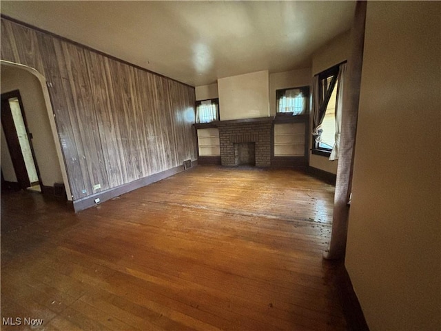 1245 E 137th St, East Cleveland, OH 44112 - unfurnished living room with visible vents, arched walkways, a fireplace, and hardwood / wood-style flooring