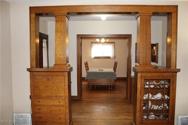 hallway featuring dark hardwood / wood-style flooring and decorative columns