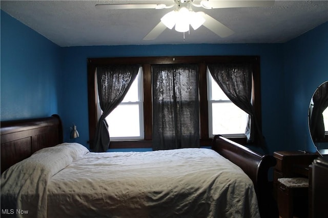 bedroom featuring ceiling fan, multiple windows, and a textured ceiling