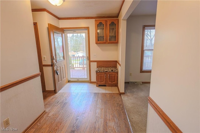 entryway with plenty of natural light, ornamental molding, and light hardwood / wood-style floors