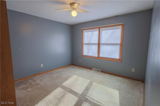 carpeted spare room featuring a textured ceiling and ceiling fan