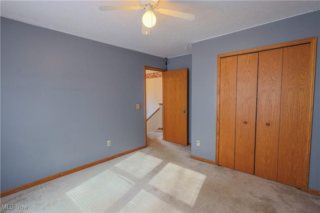 unfurnished bedroom featuring ceiling fan, light colored carpet, and a closet