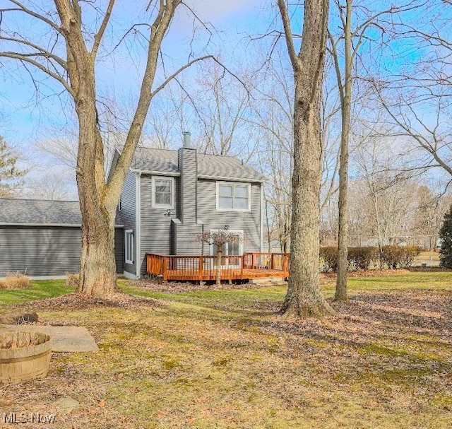 back of property featuring a deck and a lawn