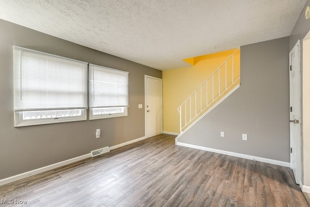 empty room with hardwood / wood-style flooring and a textured ceiling