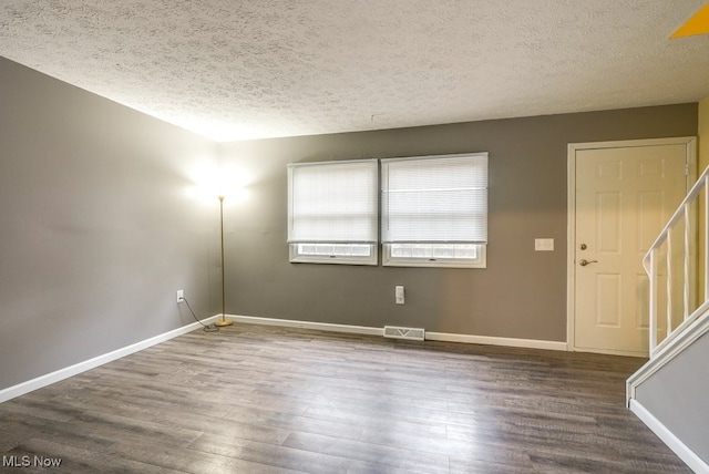 empty room with hardwood / wood-style floors and a textured ceiling