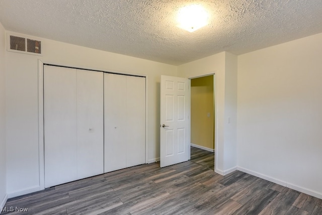 unfurnished bedroom featuring dark wood-type flooring, a textured ceiling, and a closet