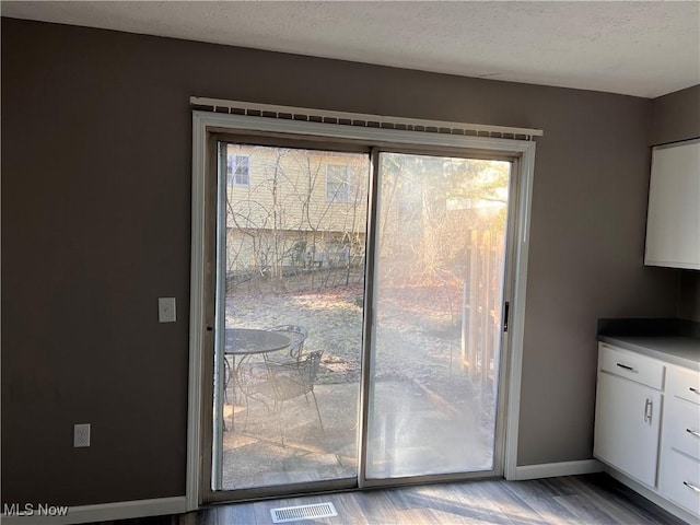 doorway to outside with a textured ceiling and light wood-type flooring