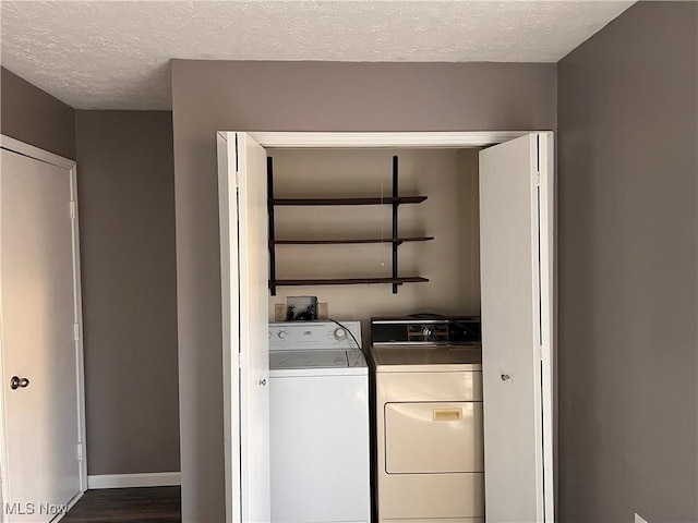 clothes washing area with dark hardwood / wood-style floors, washer and clothes dryer, and a textured ceiling