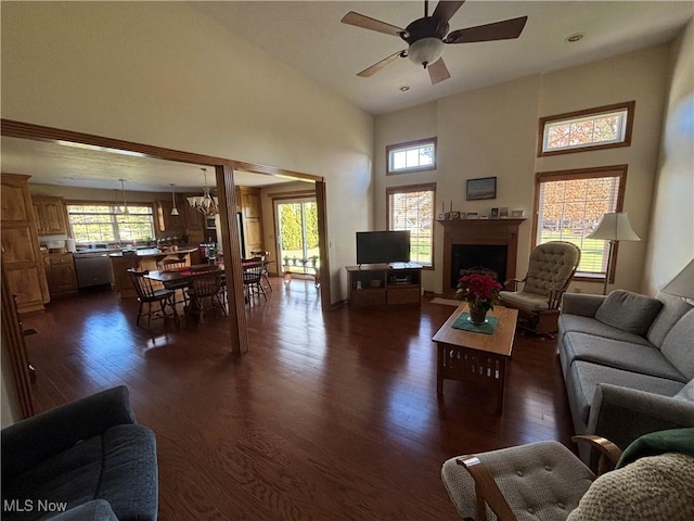 living room featuring a towering ceiling, ceiling fan with notable chandelier, and dark hardwood / wood-style flooring