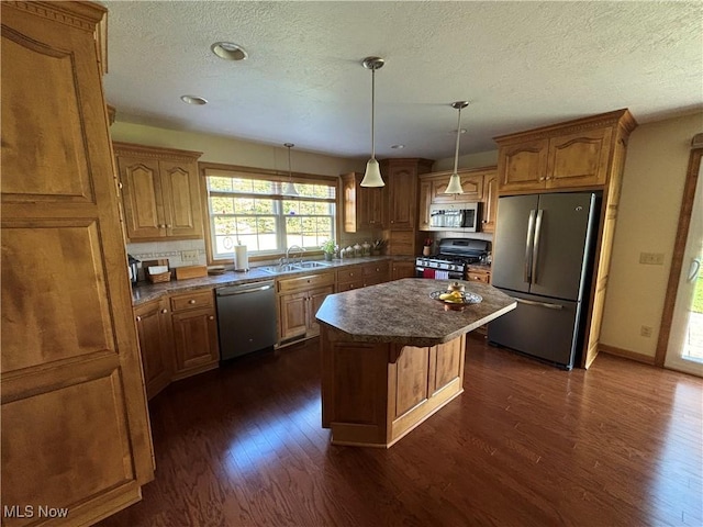 kitchen featuring sink, a center island, appliances with stainless steel finishes, dark hardwood / wood-style floors, and pendant lighting