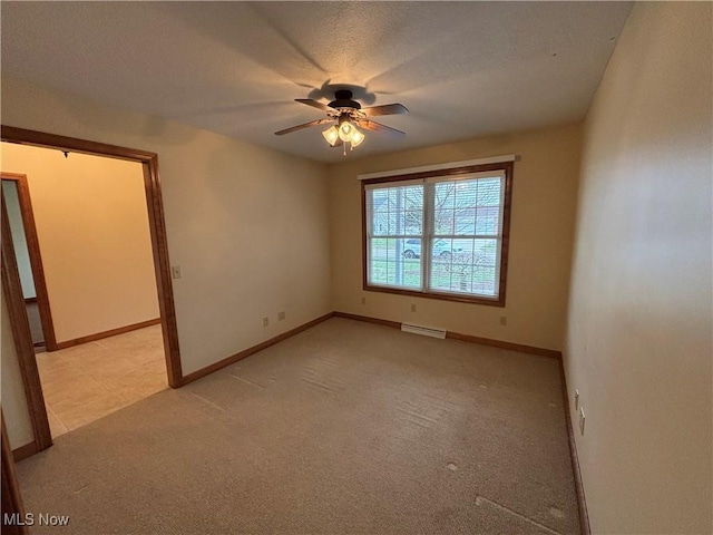 spare room featuring ceiling fan, light colored carpet, and baseboard heating