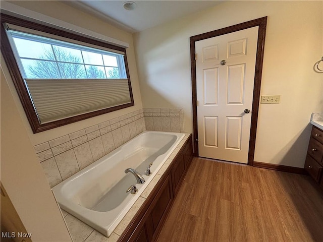 bathroom featuring vanity, hardwood / wood-style flooring, and a tub