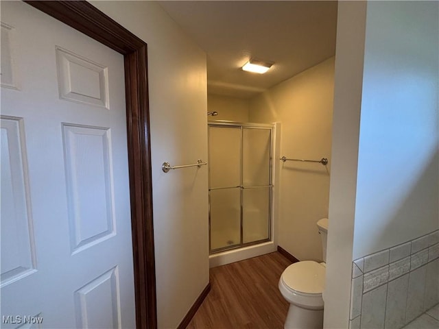 bathroom with wood-type flooring, toilet, and a shower with shower door