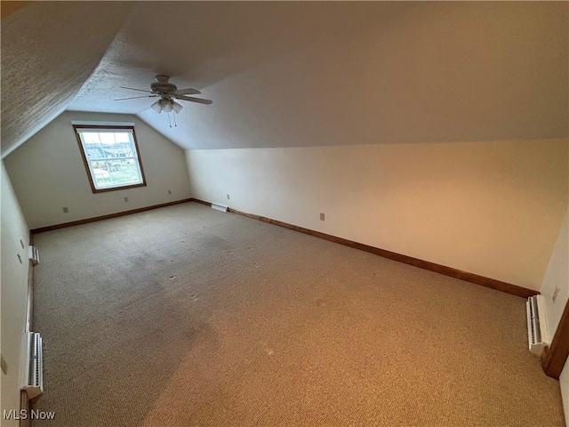 bonus room featuring ceiling fan, vaulted ceiling, a textured ceiling, and carpet