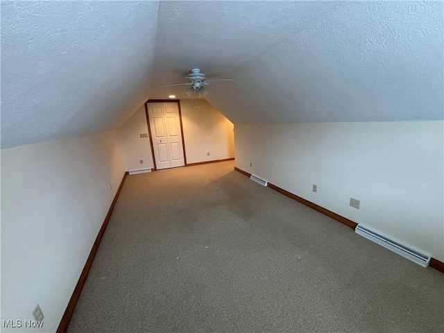 additional living space with vaulted ceiling, carpet, a textured ceiling, and baseboard heating