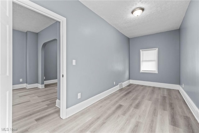 spare room with a textured ceiling and light hardwood / wood-style flooring