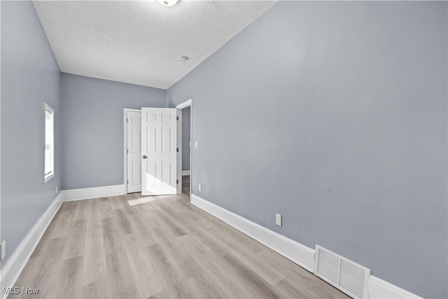 empty room featuring a textured ceiling and light hardwood / wood-style floors