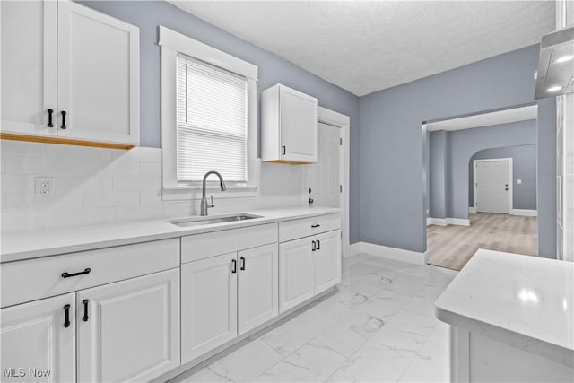 kitchen with sink, a textured ceiling, and white cabinets