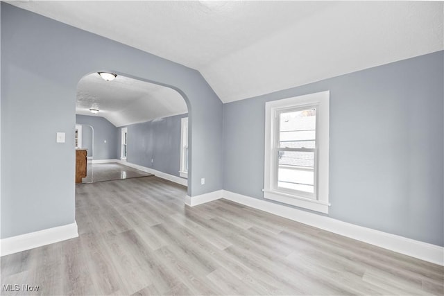 interior space featuring lofted ceiling, a textured ceiling, and light wood-type flooring