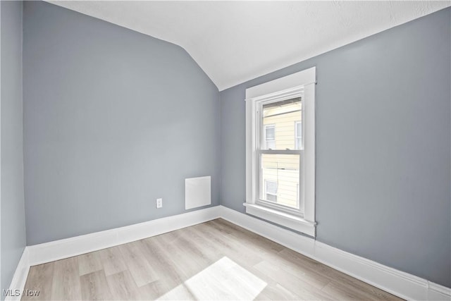 empty room with vaulted ceiling and light wood-type flooring