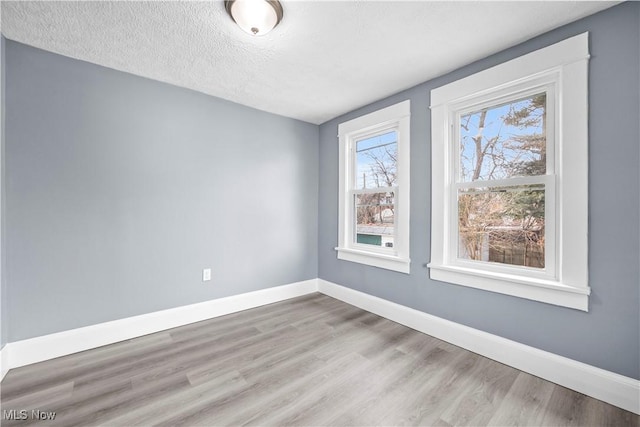 unfurnished room with light hardwood / wood-style flooring and a textured ceiling