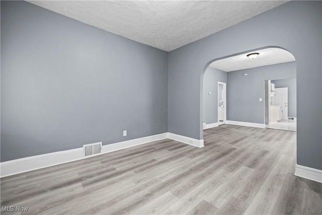 spare room featuring light hardwood / wood-style floors and a textured ceiling