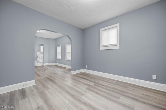 empty room with a textured ceiling and light wood-type flooring